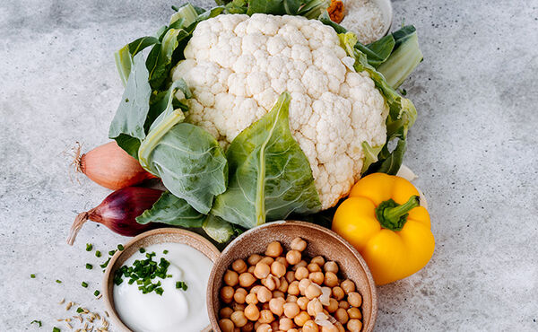 Fresh ingredients for a plant-based meal, including cauliflower, chickpeas, yellow pepper and yoghurt.